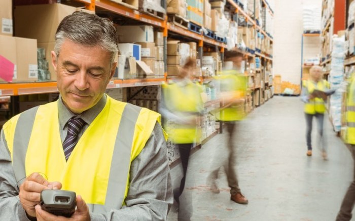 Male warehouse manager checking stock on a handheld device